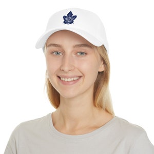 May include: A white baseball cap with a blue Toronto Maple Leafs logo embroidered on the front.
