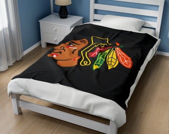 Może przedstawiać: Czarny koc z polaru z kolorowym logo Chicago Blackhawks przedstawiającym głowę Indianina i pióra.