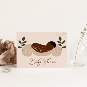 Op de afbeelding: Een lichtroze babyborrel-uitnodiging met een bruine illustratie van een baby die slaapt op een wit kussen. Aan weerszijden van de baby bevinden zich groene bladeren. De tekst "Baby Shower" staat onderaan de kaart in cursief.