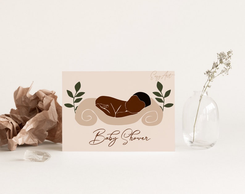 Op de afbeelding: Een lichtroze babyborrel-uitnodiging met een bruine illustratie van een baby die slaapt op een wit kussen. Aan weerszijden van de baby bevinden zich groene bladeren. De tekst "Baby Shower" staat onderaan de kaart in cursief.
