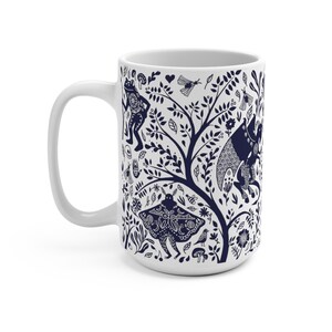 K&ouml;nnte beinhalten: Wei&szlig;e Keramiktasse mit einem marineblauen Design, das einen Baum mit Bl&auml;ttern, Blumen und verschiedenen Kreaturen zeigt, darunter einen Frosch, einen Schmetterling und einen Vogel.