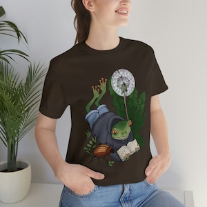 Little green frog reading a book with a beetle under a dandylion puff tee unisex t-shirt