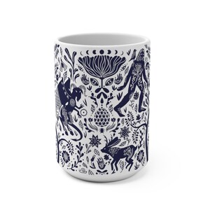 K&ouml;nnte beinhalten: Wei&szlig;e Keramiktasse mit einem blauen und wei&szlig;en Design, das eine Vielzahl von Fabelwesen und Blumenmuster zeigt.