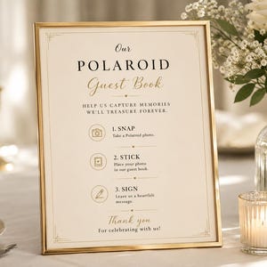 May include: A rectangular sign in a thin gold frame with cream-colored paper. The text reads: Our POLAROID Guest Book, HELP US CAPTURE MEMORIES WE'LL TREASURE FOREVER. 1. SNAP, 2. STICK, 3. SIGN, Thank you For celebrating with us! Includes icons.