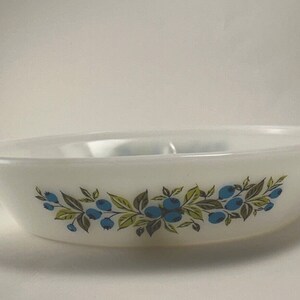 Puede incluir: Fuente ovalada blanca con un diseño de arándanos azules y verdes. El plato tiene una superficie lisa y un borde ligeramente elevado. Una pieza decorativa para servir alimentos.