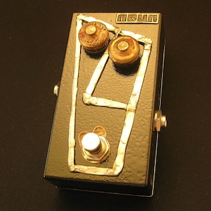May include: Black guitar effects pedal with gold trim and two knobs. The pedal has the text "T.K.I.N.T." on the top.