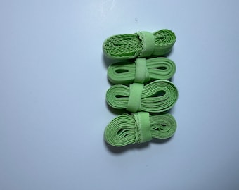 May include: Four rolls of light green elastic band, each with a white elastic band sewn around the center.
