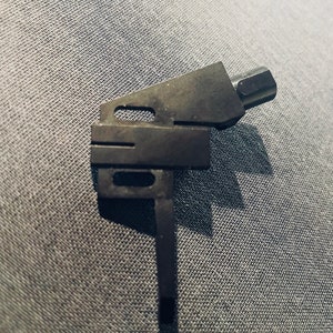 May include: Black metal tonearm for a turntable. The tonearm has a long, thin arm with a small, round head at the end.