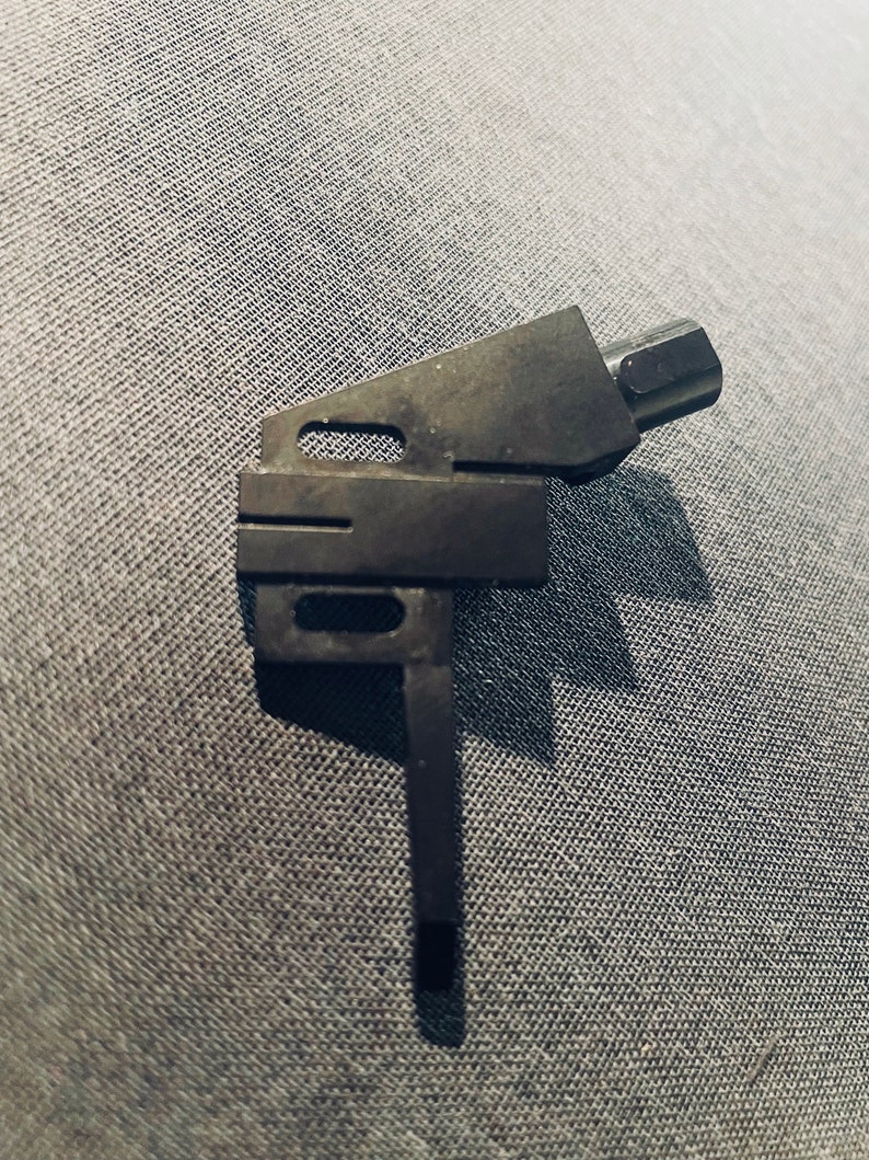 May include: Black metal tonearm for a turntable. The tonearm has a long, thin arm with a small, round head at the end.
