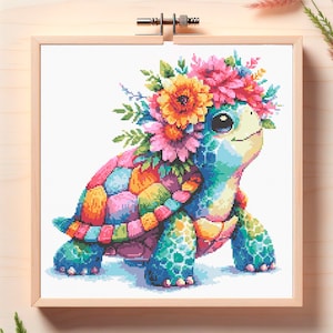 Puede incluir: Un patrón de punto de cruz colorido de una tortuga con una corona de flores. La tortuga es azul, verde, rosa y naranja. Las flores son rosas, amarillas y naranjas.