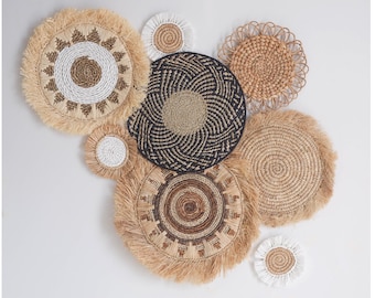 Könnte beinhalten: Eine Sammlung gewebter Wanddekorationen in verschiedenen Größen und Designs. Die Stücke weisen natürliche Farbtöne von Beige, Braun und Weiß auf, mit Fransen und komplizierten Mustern. Die Anordnung schafft eine strukturierte, böhmische Ästhetik.