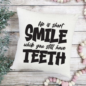 May include: White cushion with black text that reads "Life is short, Smile while you still have teeth."