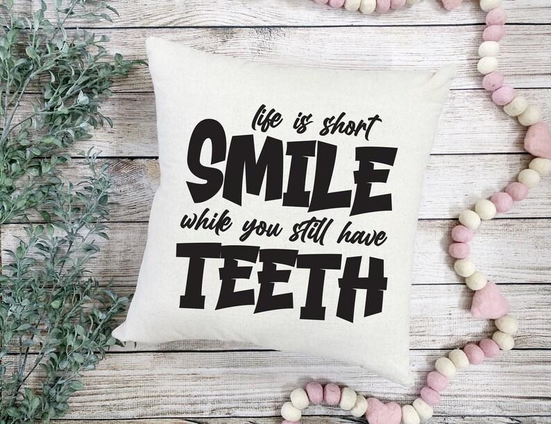 May include: White cushion with black text that reads "Life is short, Smile while you still have teeth."