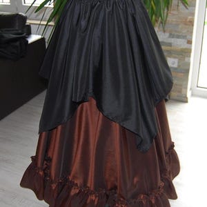 May include: A brown and black layered skirt with a ruffled hem. The skirt is made of a silky fabric and has a gathered waistband.
