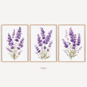 May include: Three framed watercolor prints featuring lavender bouquets. Each print showcases a cluster of purple lavender flowers with green stems and leaves against a white background. The frames are a light brown color.