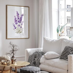 May include: A framed print featuring a watercolor painting of lavender flowers in shades of purple and green. The artwork is displayed in a living room setting with a white sofa, wooden coffee table, and decorative accents. The room has a bright, airy feel.