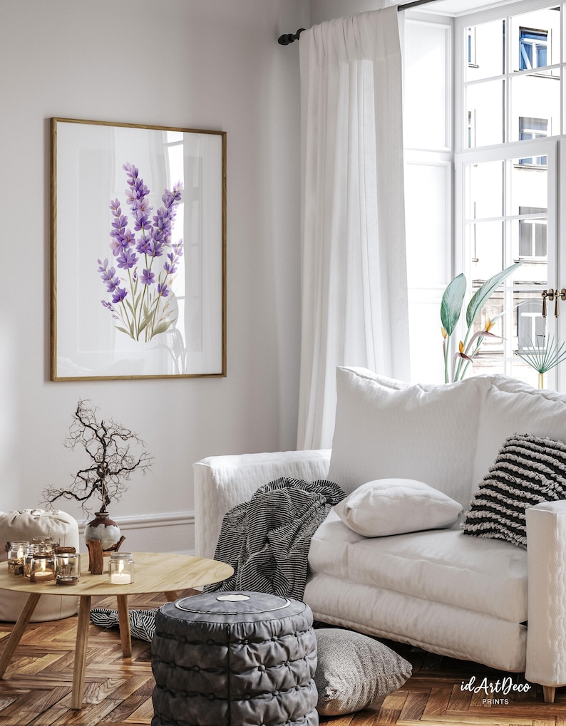 May include: A framed print featuring a watercolor painting of lavender flowers in shades of purple and green. The artwork is displayed in a living room setting with a white sofa, wooden coffee table, and decorative accents. The room has a bright, airy feel.