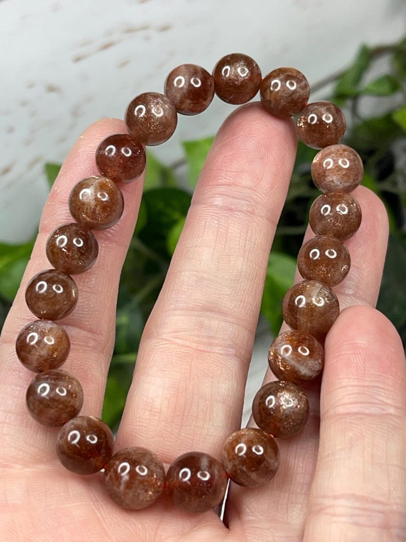 May include: A brown sunstone beaded bracelet with a polished finish. The beads are round and have a slight shimmer.