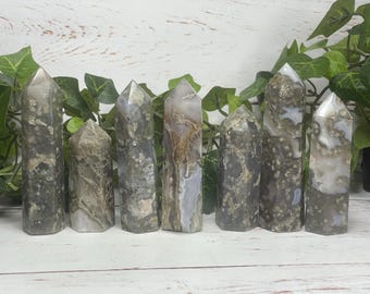 May include: A set of eight grey, white, and brown agate crystal points. The points are all different shapes and sizes, and they have a natural, rough texture.