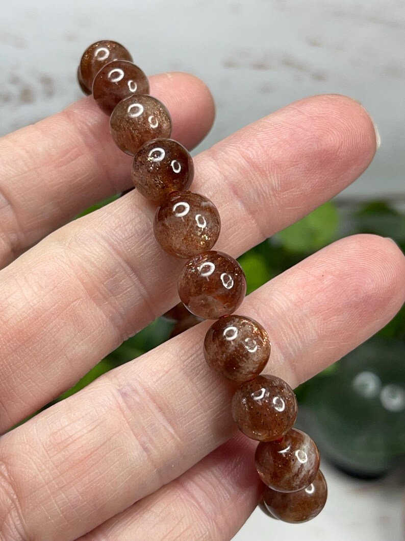 May include: A brown sunstone bracelet with round beads. The beads have a shimmery, iridescent quality.