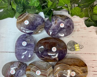 May include: Seven polished amethyst and agate stones in various shades of purple, brown, and white. The stones are oval shaped and have a smooth, polished finish.