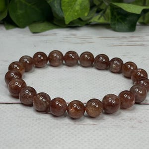 May include: A brown sunstone beaded bracelet with a stretchy elastic band.