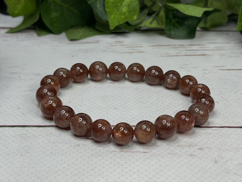 May include: A brown sunstone beaded bracelet with a stretchy elastic band.