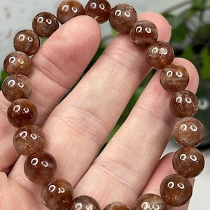 May include: A brown sunstone bracelet with round beads. The beads have a shimmery, iridescent quality.