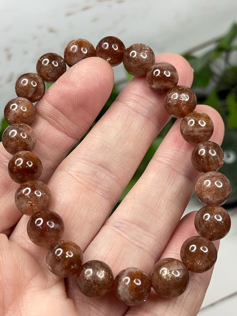 May include: A brown sunstone bracelet with round beads. The beads have a shimmery, iridescent quality.