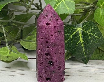 May include: A purple, pointed crystal with a rough, textured surface. The crystal has a natural, organic look and is a popular choice for crystal healing.