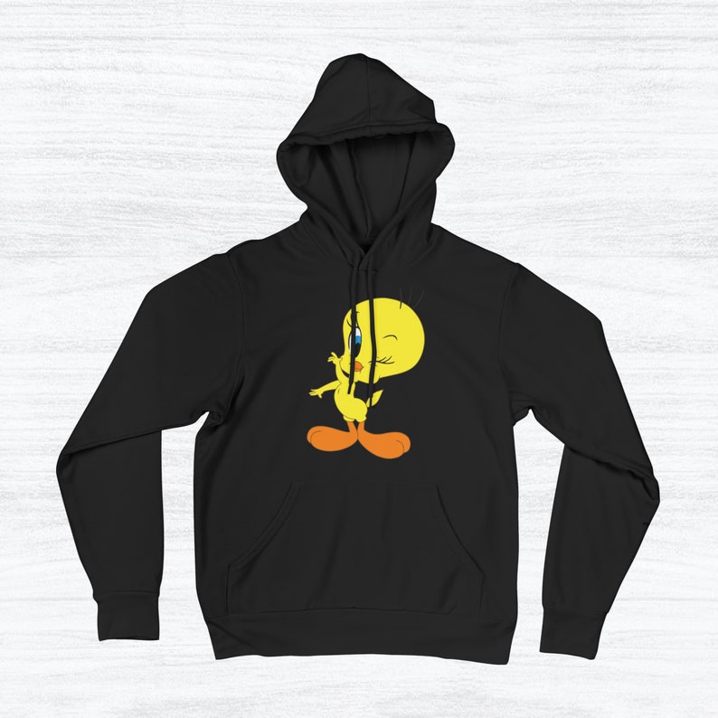 Puede incluir: Sudadera con capucha negra con un p&aacute;jaro amarillo de dibujos animados que lleva un lazo rojo y gui&ntilde;a un ojo. El p&aacute;jaro est&aacute; de pie sobre sus dos pies con las alas extendidas.
