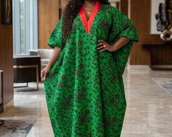 May include: A floor-length kaftan dress in a vibrant green hue, featuring a repeating pattern of small black and red stars. The garment has wide, loose sleeves and a deep V-neckline accented with a solid red collar trim, creating a flowing silhouette.