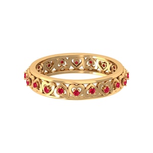 May include: A gold band ring with a delicate heart design and red gemstones. The ring is made of yellow gold and features a repeating pattern of hearts.