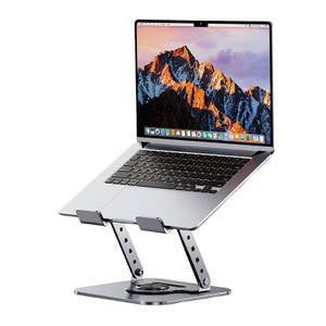 May include: A silver laptop is positioned on an adjustable, metallic laptop stand. The stand features a square base, a pivoting centre, and two angled support arms. The laptop screen shows a mountain landscape.