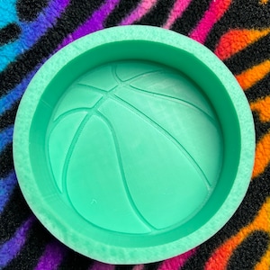 May include: A green silicone mold shaped like a basketball. The mold is designed to create a resin or soap project.