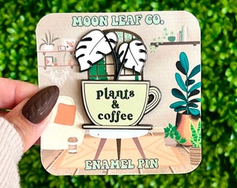 Könnte beinhalten: Eine grüne und weiße Emaille-Anstecknadel mit einer Kaffeetasse, aus der eine Pflanze wächst. Die Anstecknadel trägt den Schriftzug "Plants & Coffee" und "Enamel Pin" auf der Karte.