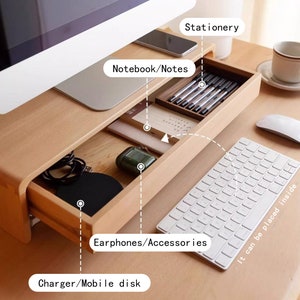 May include: A wooden desk organizer with a drawer that can be pulled out to store items like notebooks, pens, and other accessories. The drawer is labeled "Notebook/Notes", "Stationery", "Earphones/Accessories", and "Charger/Mobile disk".
