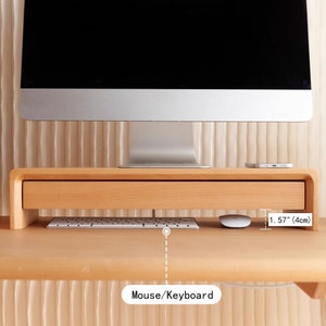 May include: Wooden monitor stand with a drawer for storing items. The stand is 1.57 inches (4 cm) tall and can hold a keyboard and mouse.