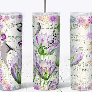 May include: A white tumbler with a floral design featuring water lilies, music notes, and a woman's face. The flowers are in shades of pink, purple, and green. The background is a white sheet music pattern.