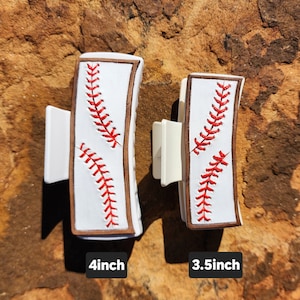 A 4inch and 3.5inch white claw clips. Both have the same leather piece on them that resemble baseball. There is a brown border with white background and red stitches