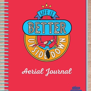 May include: Red spiral bound journal with the text "Life is Better Upside Down" in a colorful circle with a cartoon woman hanging upside down from a hoop. The text "Aerial Journal" is below the circle. The bottom right corner has a blue and white logo that says "Flying Fantastic".