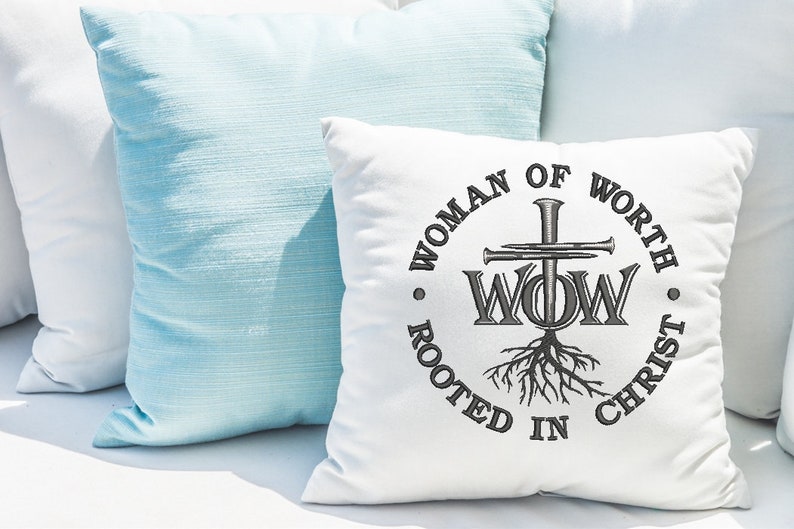 May include: White throw pillow with a black embroidered design of a cross with nails, the letters "WOW" and roots. The text around the design reads "Woman of Worth Rooted in Christ".