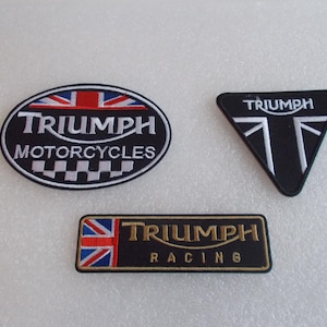 May include: Three embroidered Triumph patches. One oval patch with "Triumph Motorcycles" and a Union Jack design. A black triangle patch with "Triumph" and a Union Jack design. A rectangular patch with "Triumph Racing".