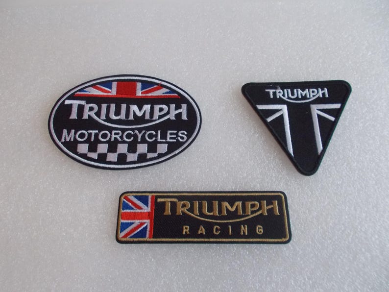 K&ouml;nnte beinhalten: Drei gestickte Triumph-Aufn&auml;her. Ein ovales Abzeichen mit "Triumph Motorcycles" und einem Union Jack-Design. Ein schwarzes dreieckiges Abzeichen mit "Triumph" und einem Union Jack-Design. Ein rechteckiges Abzeichen mit "Triumph Racing".
