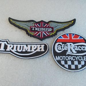 May include: Three embroidered patches featuring Triumph branding. One winged emblem with a Union Jack, one elongated Triumph logo, and one circular Cafe Racer Motorcycles patch with a checkered pattern and a Union Jack design at the top.