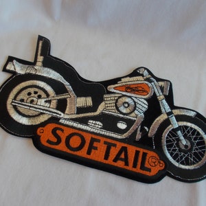 Puede incluir: Parche de moto bordado en negro y plata con la palabra "SOFTTAIL" en letras naranjas.