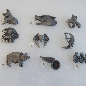 Puede incluir: Nueve pines de peltre con varios diseños, incluyendo un cerdo, un lobo, un corazón con alas, un águila, un cerdo, una motocicleta, una mujer en una luna creciente y tres monos.