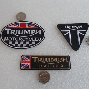 K&ouml;nnte beinhalten: Drei gestickte Triumph-Aufn&auml;her. Einer ist oval mit "Triumph Motorcycles" und einem Union-Jack-Design. Ein weiterer ist ein schwarzes Dreieck mit dem Triumph-Logo. Der dritte ist rechteckig mit "Triumph Racing".