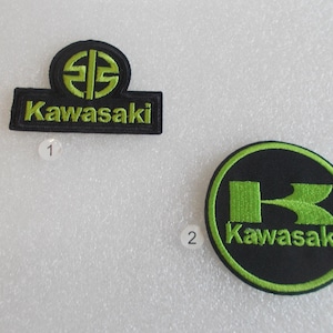 May include: Two Kawasaki patches. One is rectangular with the word "Kawasaki" in green and a green logo on top. The other is circular with a green "K" logo and the word "Kawasaki" in green.