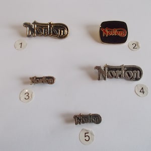 Puede incluir: Cinco pines de metal diferentes con la palabra "Norton" en ellos. Los pines están numerados del 1 al 5.